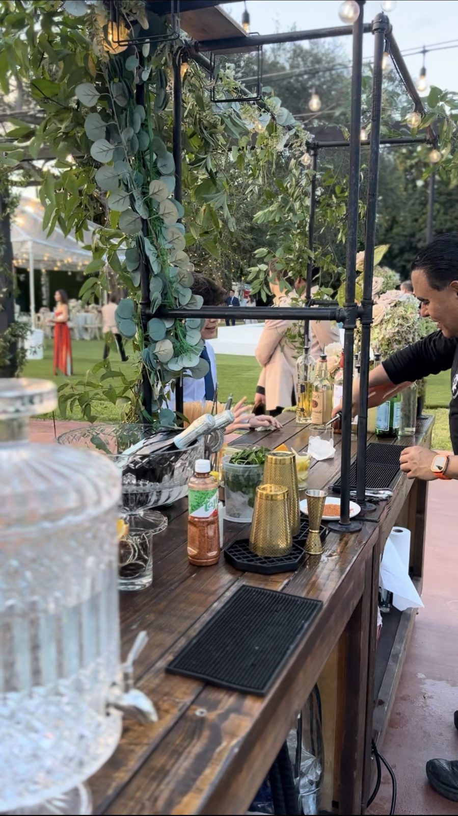 Bartender pouring a drink beside a guest in a green dress